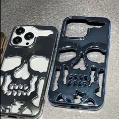 two cell phones sitting next to each other on top of a silver surface with black and white skulls