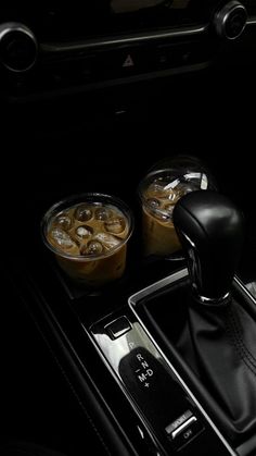 the interior of a car with two cups of coffee and an automatic gear shift control