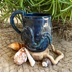 a blue mug sitting on top of a table next to sea shells