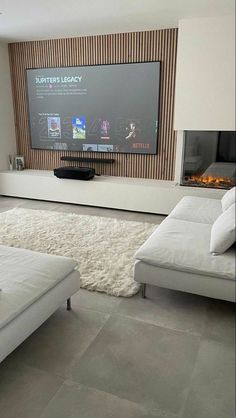 a living room with white furniture and a flat screen tv mounted on the wall above it