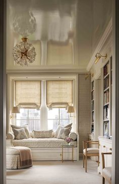 a living room filled with furniture and windows covered in roman blind shades on top of them