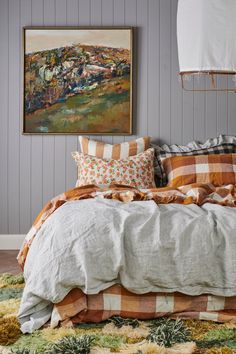 a bed with many pillows on top of it and a painting hanging above the bed