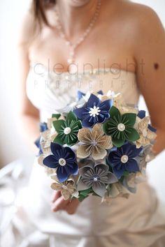 a woman in a wedding dress holding a bridal bouquet with blue and green flowers