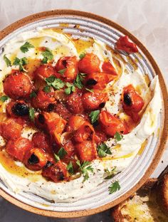 a bowl filled with food on top of a table next to bread and utensils