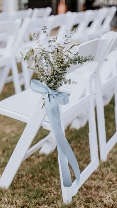 white folding chairs with blue ribbon tied around the back and flowers in vases sitting on them