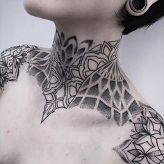 a woman's neck is covered with intricate black and white tattoos on her chest