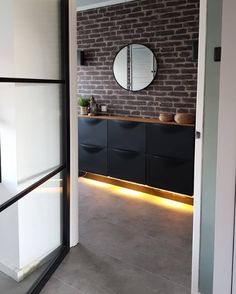 an open door leading to a bathroom with brick wall and black cabinetry in the background