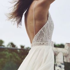 the back of a woman's wedding dress, with her hair blowing in the wind