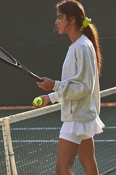 a woman holding a tennis racquet on top of a tennis court with two balls in her hand