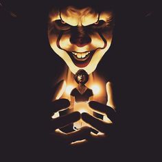 a creepy clown with his hands in front of him and the light coming from it