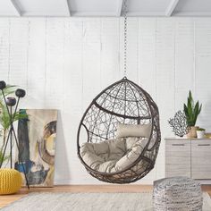 a hanging chair in the middle of a room with white walls and wooden flooring