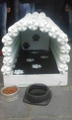 a dog house made out of foam with paw prints on it and a bowl of food next to it