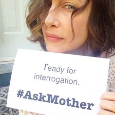 a woman holding up a sign that says, ready for interrogattion ask mother