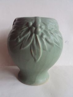 a green vase sitting on top of a white table