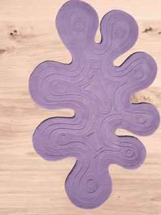 a purple rug on top of a wooden floor next to a piece of wood that has been cut in half