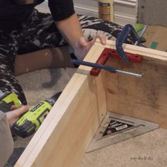 a woman is working on some wood with a hammer and screwdriver in her hand