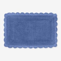 a blue bath mat with scalloped edges on a white background, top view