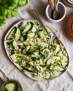 a plate full of cucumber salad next to other dishes and utensils