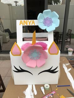 a cardboard box with paper flowers on it and an animal's face in the center