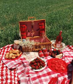 a picnic table with food and drinks on it in the grass, including strawberries