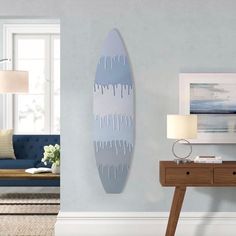 a living room with a surfboard on the wall next to a table and lamp