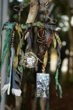 a wind chime hanging from a tree branch with feathers and beads attached to it