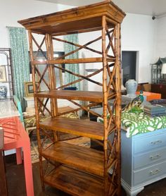 a wooden shelf sitting in the middle of a living room next to a blue dresser