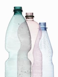 three empty water bottles are lined up against a white background, one is pink and the other is blue