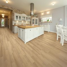 a large kitchen with white cabinets and wood flooring is pictured in this image from the dining room