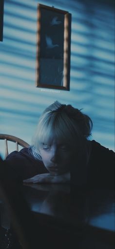 a young boy sitting at a table in front of a window with his eyes closed