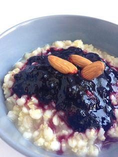 a bowl filled with oatmeal topped with blueberry sauce and almonds