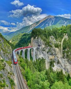 a train traveling over a bridge in the mountains