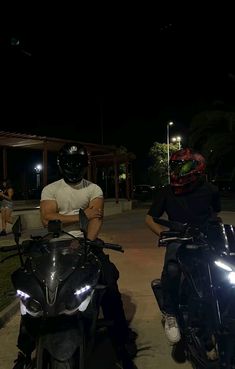 two motorcyclists are sitting on their bikes at night