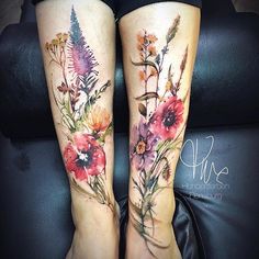 two women's legs with flowers and leaves tattooed on their legs, both showing the same