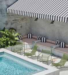 an outdoor pool with lounge chairs next to it and a striped awning on the roof