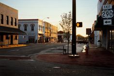 an empty street with buildings and signs on the side walk in front of it at sunset