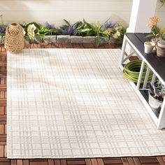 a white rug on the ground in front of a planter and potted plants