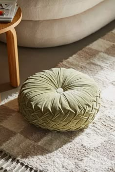 a green round pillow sitting on top of a rug next to a table and chair