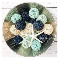 a bowl filled with blue and white yarn balls next to a starfish on top of a wooden table