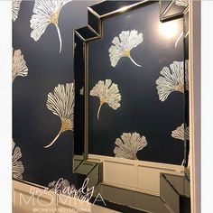 a bathroom with blue walls and white flowers painted on the wall next to the mirror