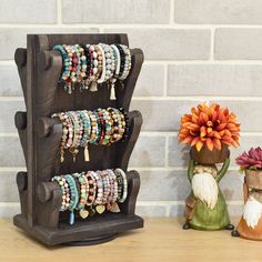 a wooden stand with bracelets and flowers on it