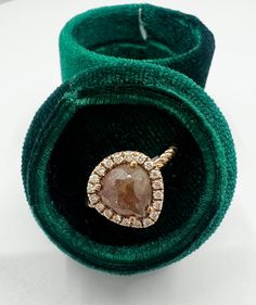 an engagement ring with a large brown diamond in it's velvet band and inside its green velvet case