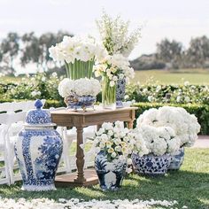 blue and white vases with flowers are sitting on the grass in front of chairs