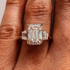 a woman's hand holding an emerald and diamond ring