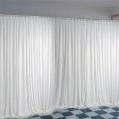 an empty room with checkered floor and white curtains