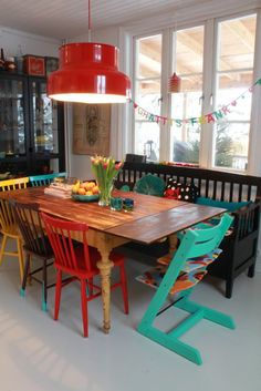 a dining room table with colorful chairs and a red light hanging from the ceiling over it