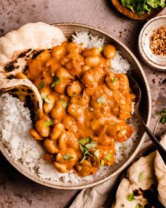 a bowl filled with rice and beans on top of a table next to pita bread