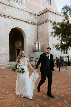 a bride and groom holding hands in front of a building