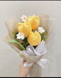 a person holding a bouquet of flowers made out of crocheted yarn and paper