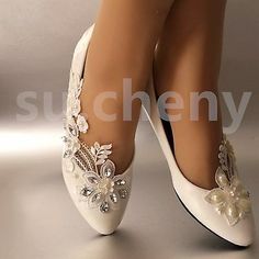 a woman's legs wearing white shoes with pearls and flowers on the heels